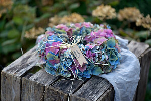 Colorful hydrangea wreath on a rustic wooden box in the garden