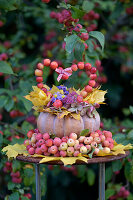 Herbstdekoration aus Kürbis, Zieräpfeln und Blättern und einer Herzform aus Äpfeln