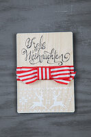 Wooden sign with Merry Christmas" lettering and red and white bow"