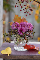 Strauß aus Chrysanthemen (Chrysanthemum), Wildem Wein mit Hagebutten in Glasvase