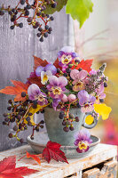 Strauß von Stiefmütterchen (Viola wittrockiana), Schneebeere und Wildem Wein in Tasse