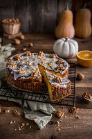 Pumpkin cheesecake topped with icing and decorated with walnuts
