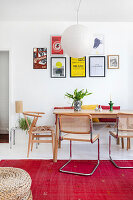 Dining room with colourful pictures, rattan chairs and red carpet