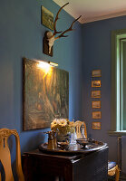 Blue room with antique furniture, antlers and illuminated painting