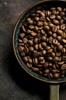 Ganze geröstete Kaffeebohnen in rustikaler Pfanne