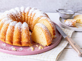 Quark bundt cake on a pink plate dusted with icing sugar