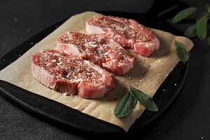 Raw pork neck steaks with salt and pepper