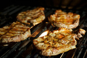 Four porks shoulder steaks on the barbeque