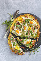 Cauliflower pizza with asparagus, eggs, bacon and peas