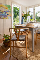 Dining area with wooden table, chairs and plants, view of the garden