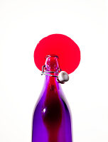 Rote Flüssigkeit läuft aus lila Flasche
