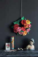DIY paper wreath with paper roses on a dark wall with vintage decorations