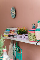 Decorative wall shelf with books, plants and colourful wicker bottles