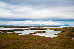 Lake and desolate landscape with mountains in background, Thingvellir, Iceland