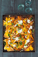 Colourful nacho tray with cheese and sour cream