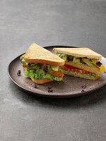 Sandwich with tempeh, avocado, tomatoes and herbs