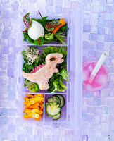 Bento box with dinosaur sandwich and vegetables