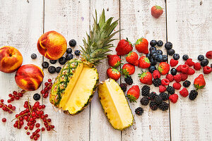 Sliced pineapple and mixed berries on a wooden surface