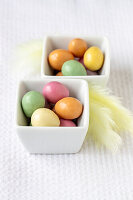 Colourful dragee eggs in porcelain bowls