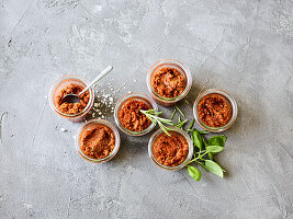 Pesto Rosso in small jars with fresh herbs