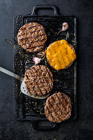 Grilled burger patties with melted cheese on a cast iron griddle