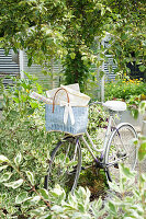 Fahrrad mit blauem Korb im sommerlichen Garten