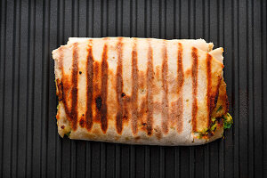 Burrito with guacamole and minced meat and vegetable filling