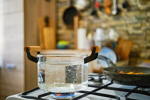 Water boiling in a glass pot on a gas stove