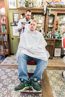 Professioneel barbier verzorgt het haar van een van zijn mannelijke klanten in de barbershop.