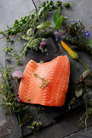 Raw salmon fillet with fresh herbs and flowers