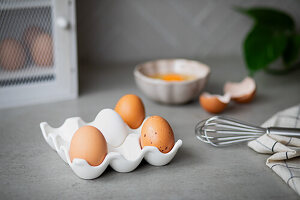 Fresh eggs in an egg carton, cracked egg