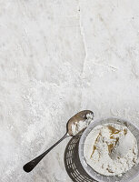 Tablespoon next to a sieve with dough mixture on marble slab