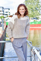 Rothaarige Frau in braun-beigem Strickpullover mit Lochmuster und grauer Chino