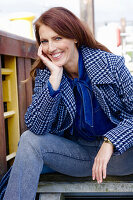 Rothaarige Frau in blau-karierter Jacke und Jeans