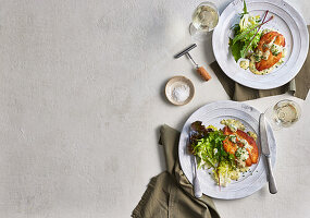 Gegrillter Fisch mit grünen Salatblättern und heller Sauce