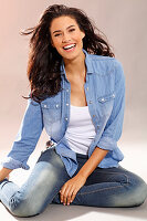 Young woman in denim shirt and trousers, sitting