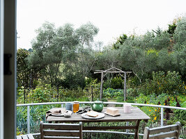 Gedeckter Frühstückstisch auf Balkon mit Blick in grünen Garten