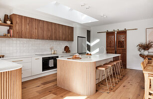 Modern kitchen with wooden fronts and kitchen island with bar stools