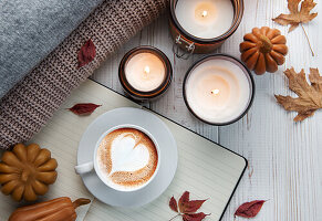 Herbstlicher Flachbildschirm mit Kaffee, Keksen, Herbstblättern und Kerzen auf Holz