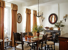 Esszimmer mit dunklem Holztisch, Polsterstühlen und goldenen Vorhängen