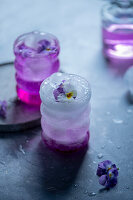 Frühlingscocktail mit Eis und Stiefmütterchenblüten