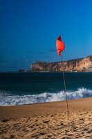 Rote Flagge am Strand von Nazare, Portugal