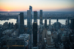 Skyscrapers against sea and sky in city during sunset