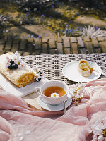 A delicious Swiss roll filled with rich dulce de leche is presented on a garden table, accompanied by tea and spring flowers.