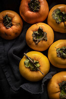 Frische Kaki (Diospyros kaki) auf dunklem Tuch