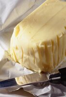 Ein ganzes Stück Butter mit Messer auf Butterpapier