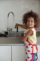 Kleines Mädchen wäscht Obst unter fliessendem Wasser
