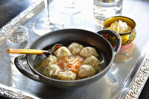 Suppe mit Garnelenwontons, geriebenen Karotten und Weisskohl