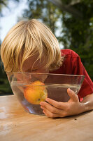 Junge isst einen Apfel in einer Schüssel mit Wasser, Kindergeburtstag