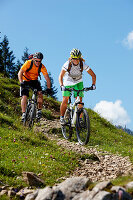 Man and woman riding mountain bikes downhill, Spitzingsee, Bavaria, Germany